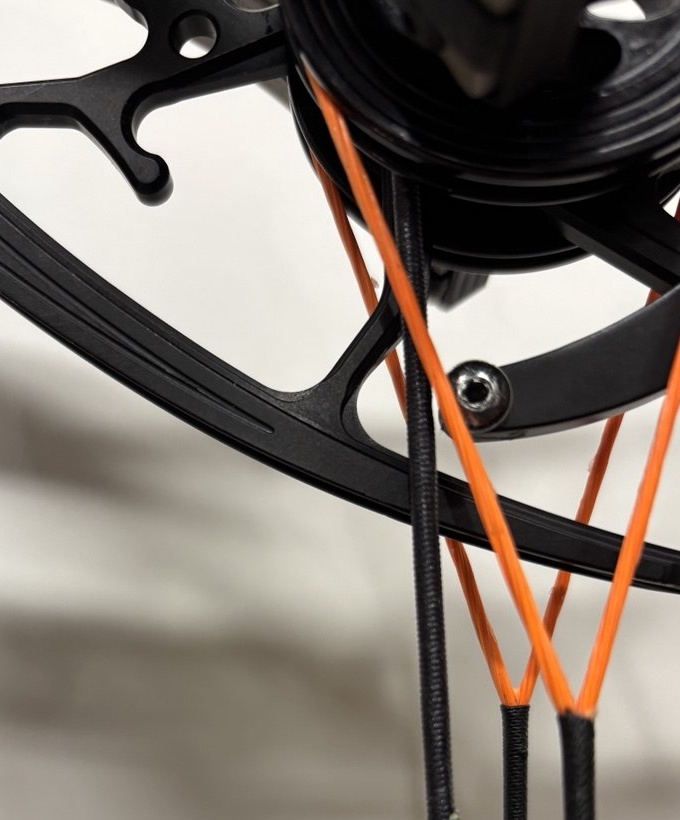 Tight crop of a compound bow cam area with the string and cables visible near the timing-reference region.