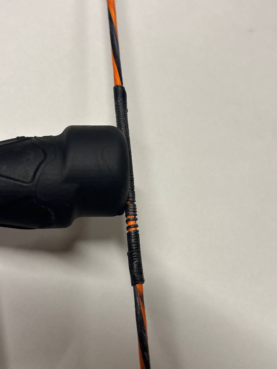Bowstring loop end served over a metal limb tip — worn wraps showing before replacement
