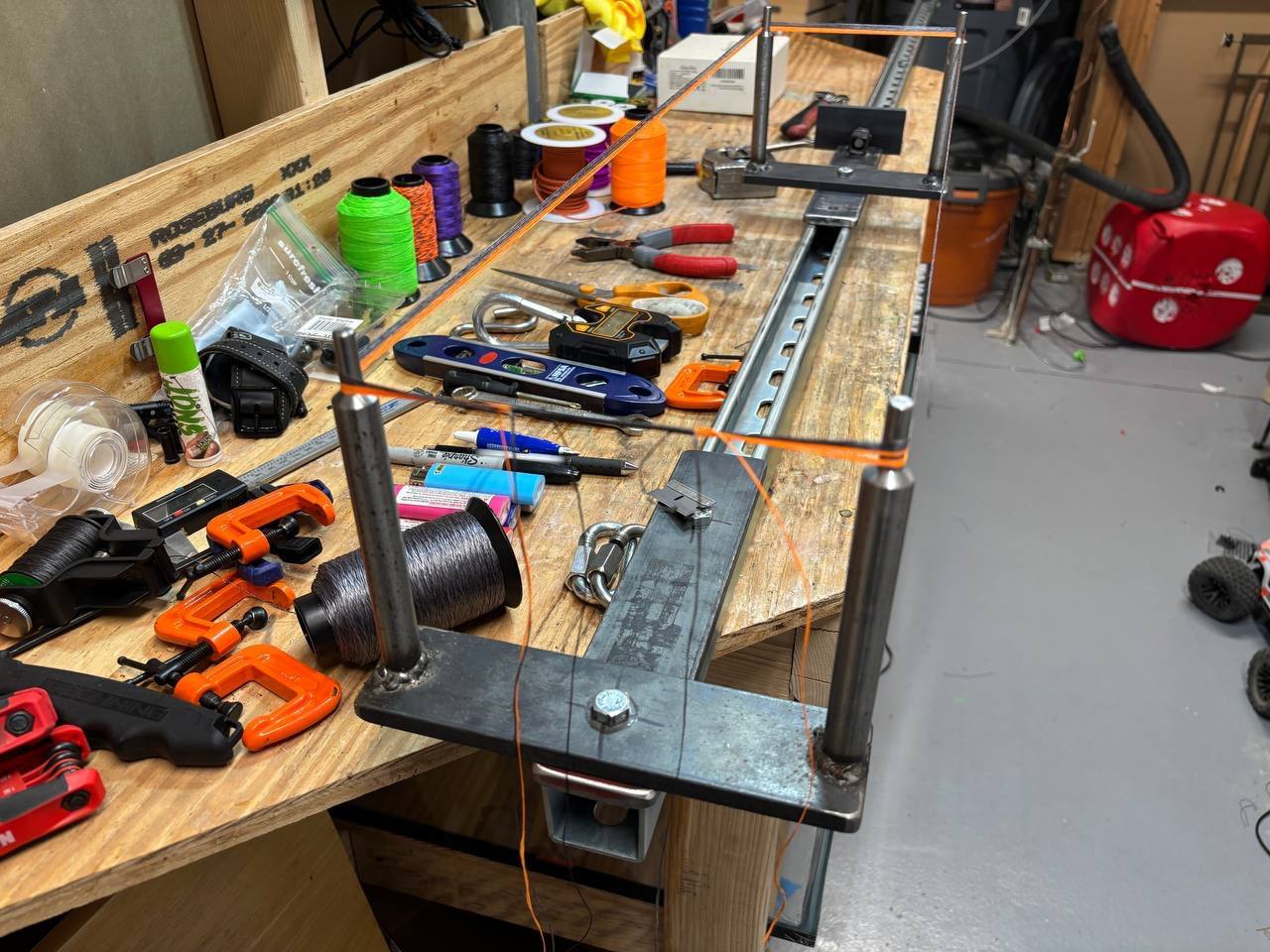 A full bench view of the loaded string jig with the pivoting end assemblies visible before the posts are turned for serving access.