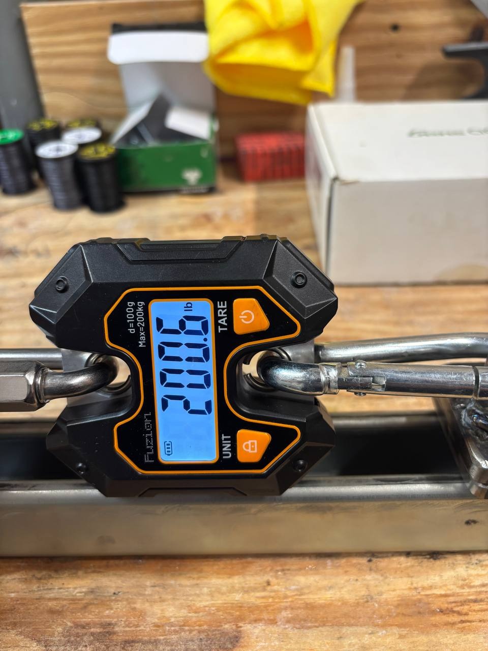 A digital hanging scale reading 200.6 pounds while connected to the tensioning jig.